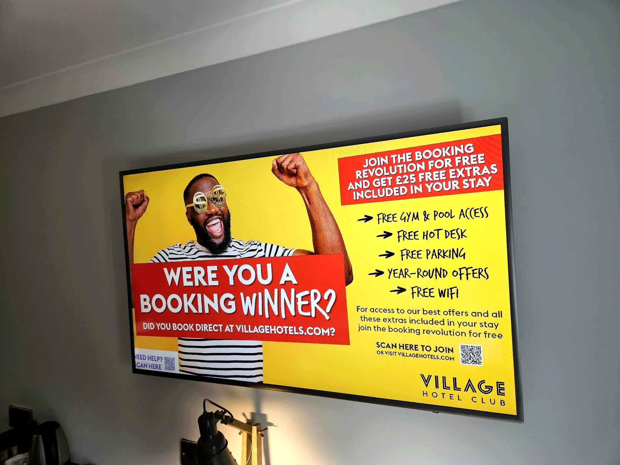 Village Hotels bedroom display with hotel promotional screen
